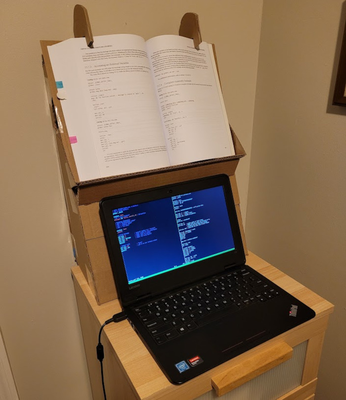 tall book stand displays book above a laptop screen