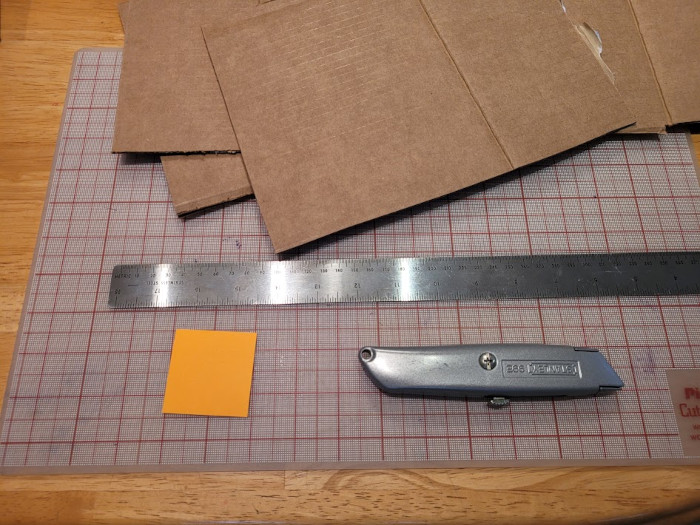 photo of materials: utility knife; cutting mat; cardboard; ruler; sticky notes