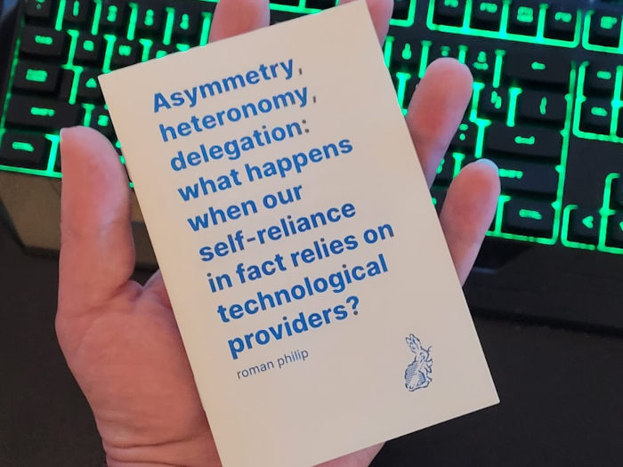 My hand holding the printed booklet. A keyboard with glowing green keycaps is in the background.